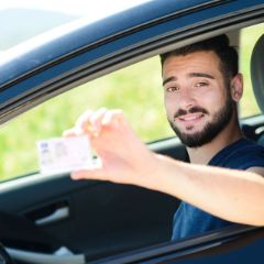 Grafik: Junger Mann lächelt und hält seinen Führerschein hoch